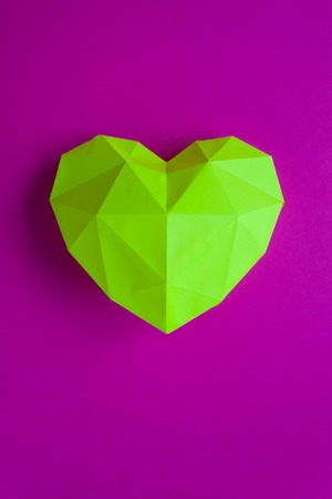Yellow polygonal heart made of paper on purple backgroundの写真素材