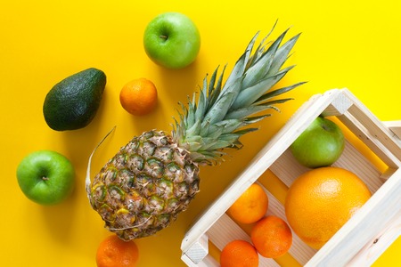 tropical fruits in wooden box on yellow backgroundの写真素材