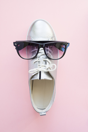 silver sneakers with glasses on pale pink backgroundの写真素材