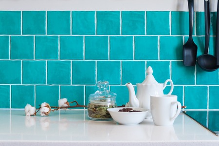 Modern gray kitchen features dark gray flat front cabinets paired with white quartz countertops and a glossy blue care tile.の写真素材
