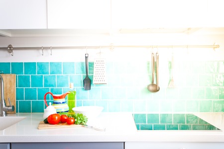 Modern gray kitchen features dark gray flat front cabinets paired with white quartz countertops and a glossy blue care tile.の写真素材