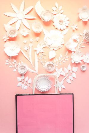 Paper bag of different paper flower on a pink background. Shopping. Top view. Flat layの写真素材