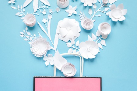 Paper bag of different paper flower on a blue background. Shopping. Top view. Flat layの写真素材