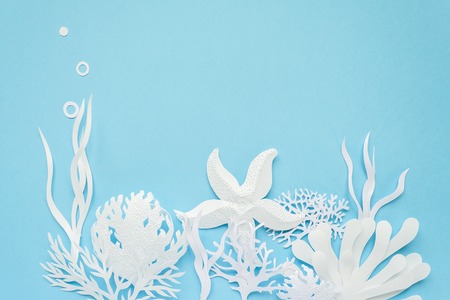 Underwater landscape cut from white paper on blue background. The ocean and the undersea world with different inhabitants, corals and starfishの写真素材