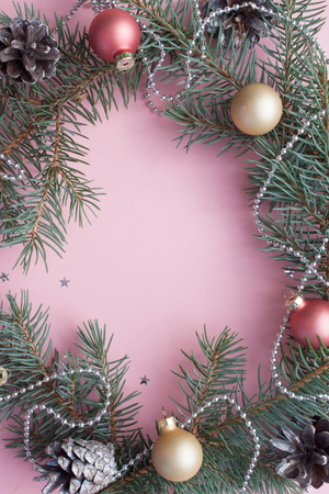 Merry Christmas and Happy New Year. Frame Christmas Card Festive with green Fir Branches and Holiday Object on pale pink Background.の写真素材