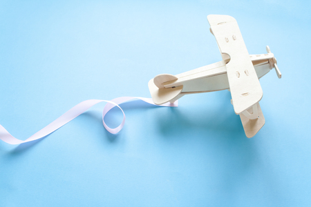 Eco concept. Wooden children's plane with pink ribbon on a blue backgroundの写真素材