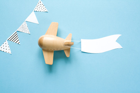 Childrens wooden plane in the sky carries an empty banner.の写真素材