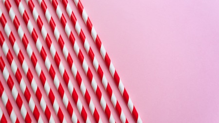 Red and White striped straws on pink background. Holiday conceptの写真素材