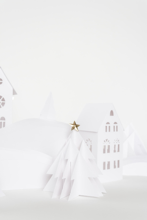 Winter wonderland made of white paper. Christmas tree of white paper decorated with a gold star. Christmas holidays conceptの写真素材