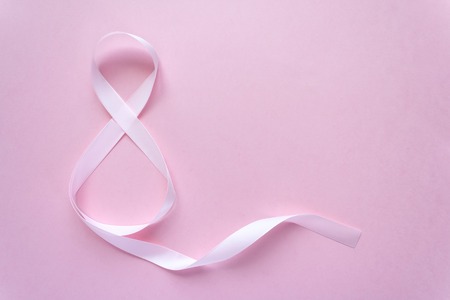 Rose gift celebration ribbon in 8 digit shape over pale pink backgroundの写真素材