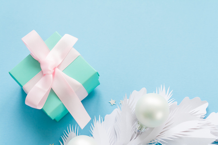 Merry Christmas and Happy New Year. Christmas Card Festive with white Fir Branches made of paper and Holiday pearl balls and beautiful gift on blue Background.の写真素材