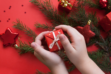children's hands holding a gift on a red backgroundの写真素材
