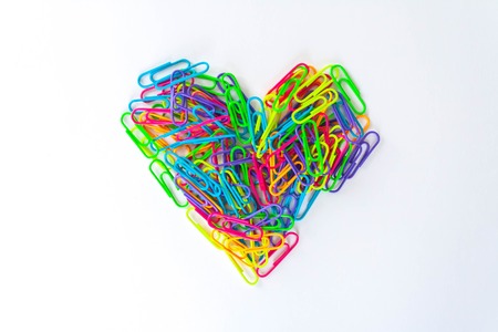 Colorful paper clips lined in heart shape on white background. Selective focusの写真素材