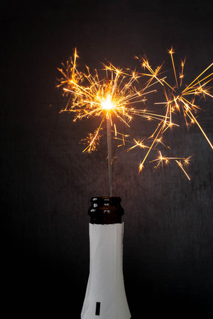 Champagne bottle with bengal fire popping on black background. Holiday concept. Fireworksの写真素材