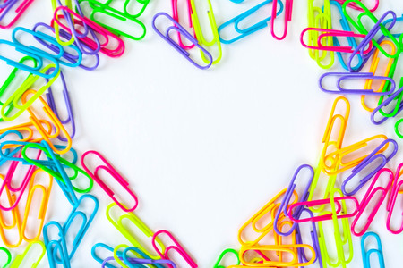 Colorful paper clips lined in heart shape on white background. Selective focusの写真素材