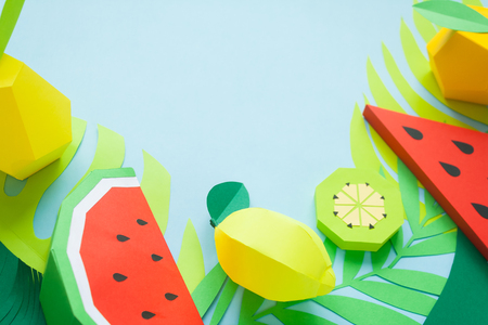 exotic fruits made of paper on blue background with green tropical leavesの写真素材