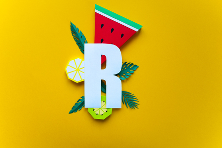 Yellow letter r cut out of paper with paper tropical fruit on white background. Form, counterformの写真素材