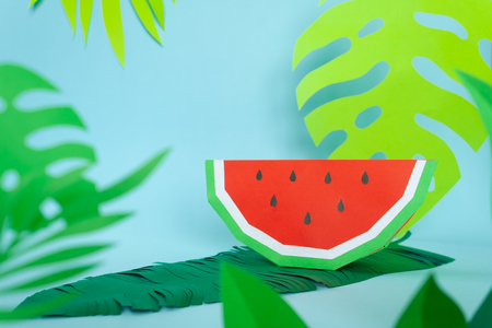 Watermelon made of paper with tropical leaves on blue background. Summer conceptの写真素材