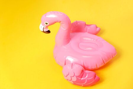 Inflatable pink flamingos on a bright yellow background.