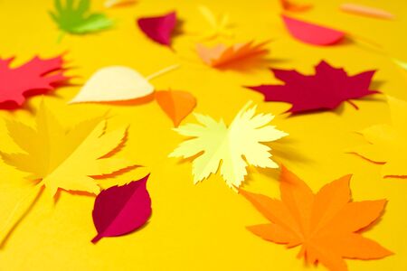 Leaves of paper fall red, orange, yellow leaf fall. Yellow background. Handmade origami.の写真素材