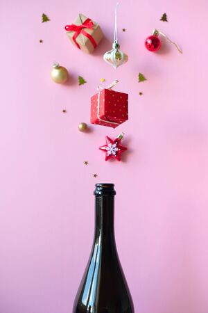 Champagne bottle with different christmas decoration on pink background. New year concept.の写真素材