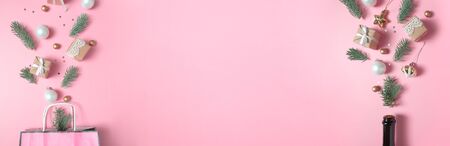 Champagne bottle and Package with different christmas gold and white decoration on pink background. Open champagne concept. Flat lay. Long format for webの写真素材