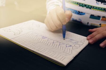 5 years old child writes the recipe at the table. Close up