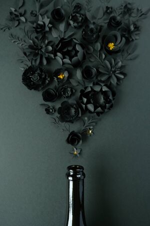 Champagne bottle with different black paper flower on black background.の写真素材