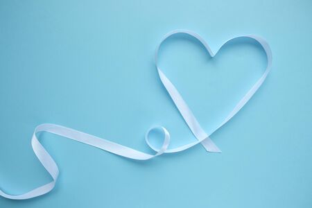 white ribbon in the shape of a heart on a blue background