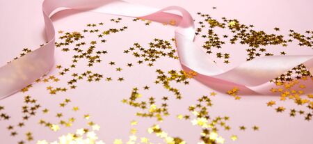 Christmas or New Year decoration background: gold stars on pink background with copy space