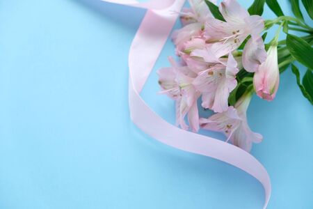 Cookies in the shape of an angel with a pink ribbon with lisianthuses on a blue background.の写真素材