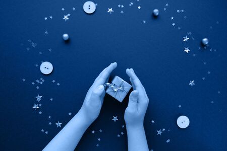 Christmas or New Year. Children's hands holding a Christmas gift. The concept of giving. Trend color of the year 2020 classic blue. Tonedの写真素材