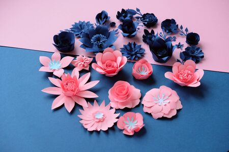 Blue paper and pink paper flowers on dark blue and pink background. Cut from paper.