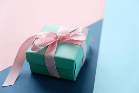 Blue gift close-up tied with pink ribbon on blue and classic blue backgroundの写真素材