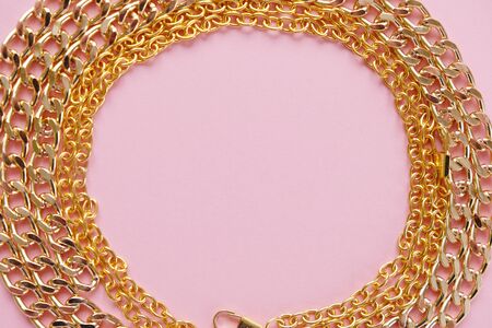 chain and heart, a gold chain laid out in the shape of a heart on a pink background. Female background.の写真素材
