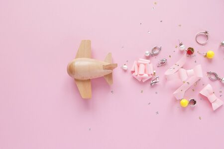 small wooden toy airplane carries female accessories on pink background. The concept of spring and...