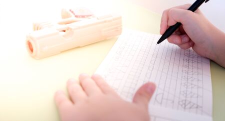 5 years old child writes the recipe at the table. Close up