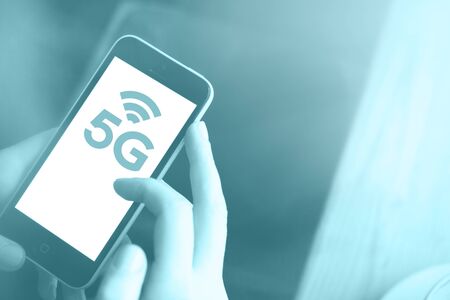 5G High speed internet network communication, man using mobile smartphone with 5G icons flow on virtual screen, worldwide connection. Internet of Things, IoT concept. Trend color of the year 2020 purist blue. Tonedのeditorial素材