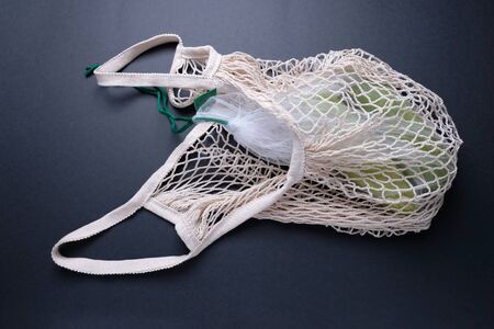 Composition with zucchini in a string bag on a black background. Eco concept, healthy food,...