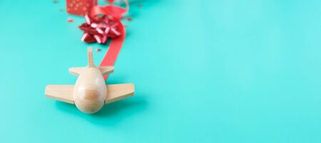 A small wooden toy airplane carries Valentine's elements. Vapor trail of sequins in the shape of...