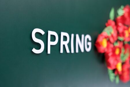 Hello, spring. With red paper flowers and green leaves on dark green background.の写真素材