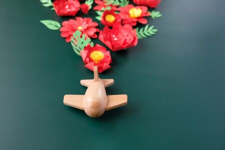 Hello, spring. Wooden toy airplane lucky red flower cut from paper. The concept of spring and travel
