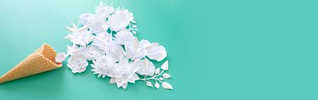 Waffle cone with paper flowers on blue background. Holiday concept.