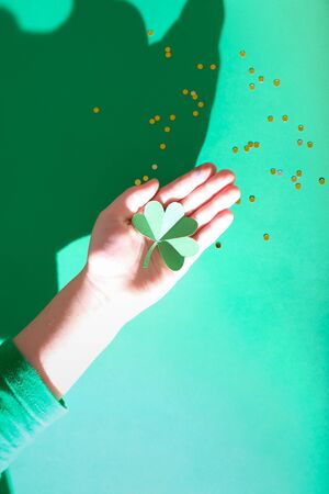 St. Patrick's day, children's hands hold a clover on a green background with the symbols of St. Patrickの写真素材