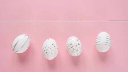 White easter eggs with silver decor on pink background. Happy Easter concept. Long format for web