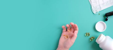 The child's hand holds a dose of vitamins in the hand on blue background