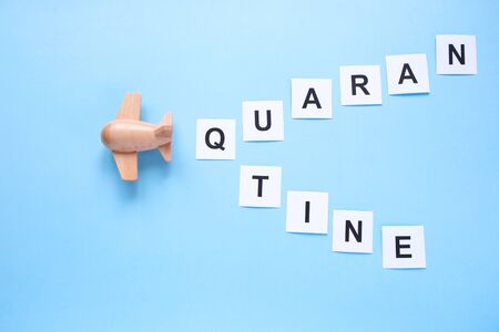 A small wooden plane carries a sign about quarantine. Mass notification. Concept of quarantine and isolationの写真素材