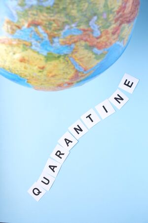 The concept of a worldwide quarantine. Globe and the word quarantine on a blue backgroundの写真素材
