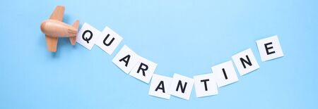 A small wooden plane carries a sign about quarantine. Mass notification. Concept of quarantine and isolation. Long format for webの写真素材