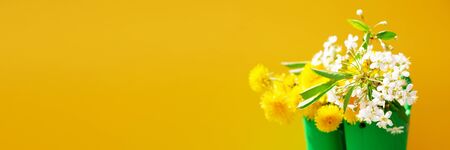 Hello, summer concept. Green rubber boots with yellow flowers on yellow background
